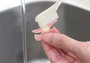 義歯をブラシで洗う